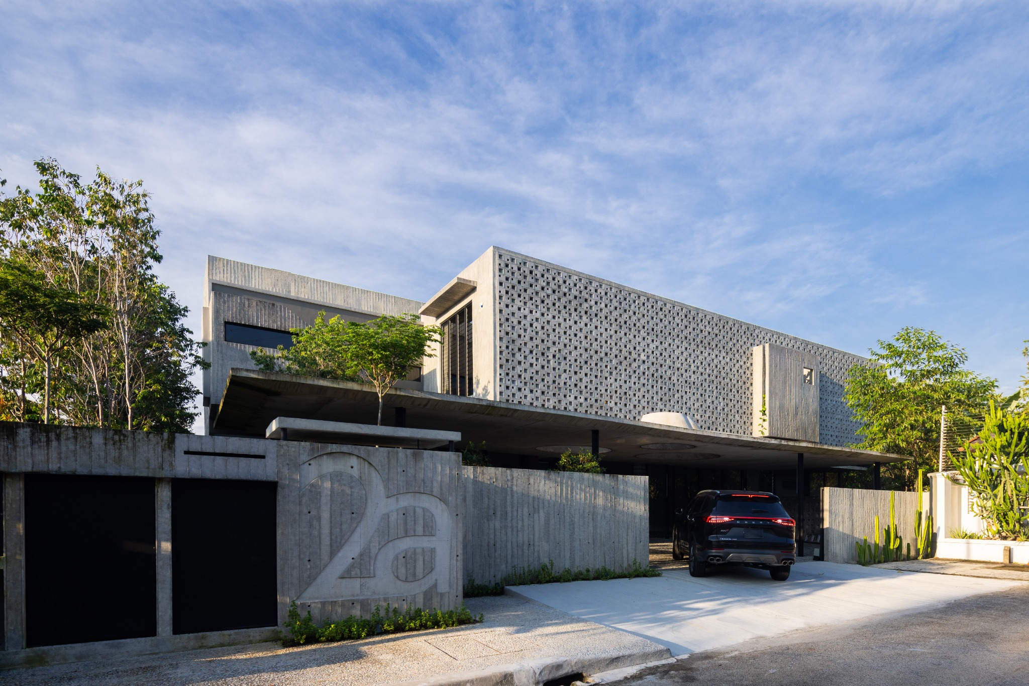 Tropical Shift House: concrete street facade and screened upper floor.